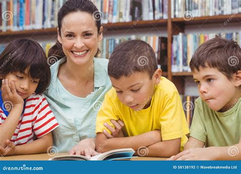 Alumnos Y Libro De Lectura Del Profesor En Biblioteca Foto De Archivo