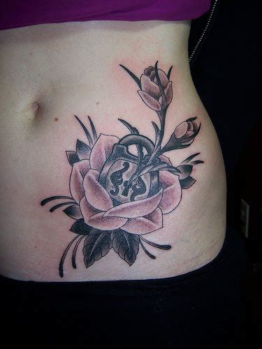 Black rose tattoos done beautifully on her back with thorns and black leaves. Hip Rose Tattoos - Tattoo Design