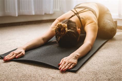 Try these beginner yoga poses for starters. Young girl practicing yoga in the morning sunlight at home ...