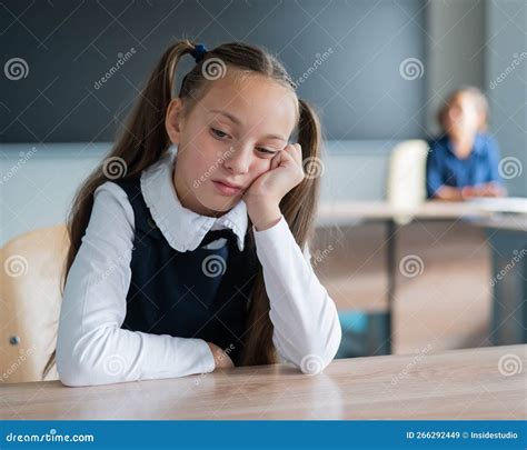 little caucasian girl is bored at the lesson at school the schoolgirl is sitting at her desk
