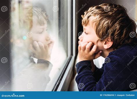 Portrait Of Boy Looking Out The Window Of His House Bored Respecting