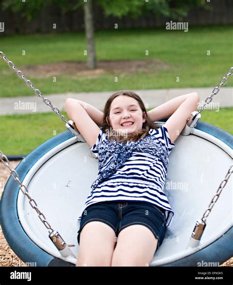 Teenage Girl Swings On A Saucer Swing At A Park Playground Stock Photo