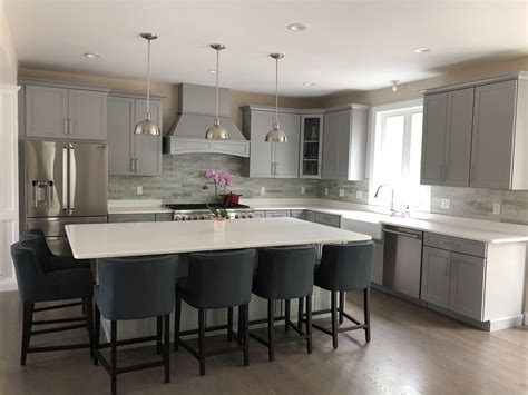 This small kitchen has several open shelves supported by l black iron brackets in retro industrial styles. Gray kitchen cabinets with white quartz island and ...