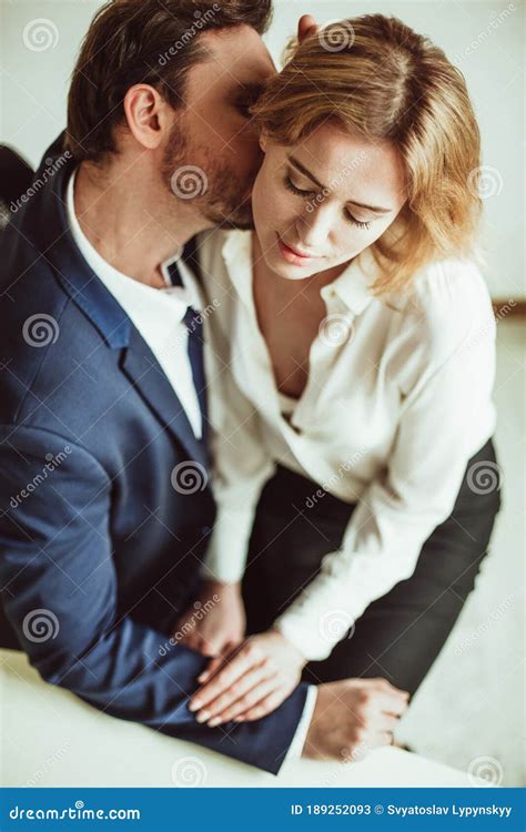 amorío en el trabajo hombre de negocios besa el cuello de una mujer sentada en su regazo dos