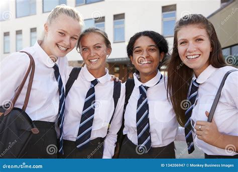 Female High School Teacher Sitting At Table With Teenage Pupils Wearing