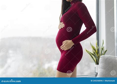 pregnant woman profile holding her belly in red dress beautiful model for pregnancy maternity