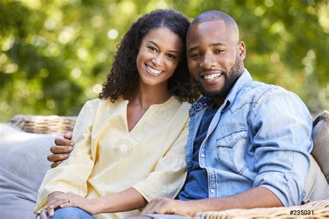 Happy Young Black Couple Sitting And Embracing In The Garden Stock