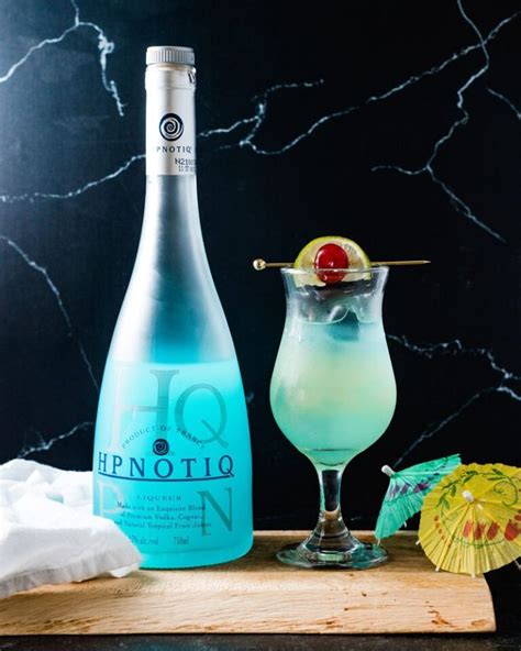 A Bottle Of Gino Next To A Cocktail Glass With An Umbrella On The Table