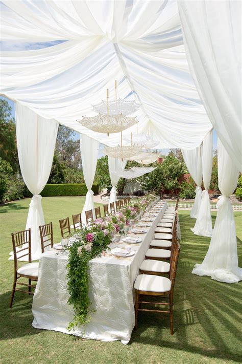 Long Table With Greenery And Flower Table Runner With Lace Parasols