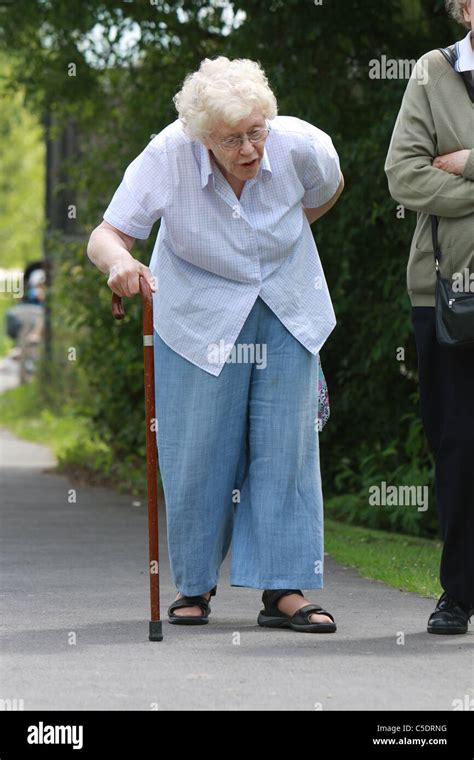 An Old Lady Walking With The Aid Of A Walking Stick Stock Photo