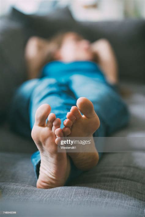 Feet Of Relaxed Young Woman Lying On Couch At Home Photo Getty Images