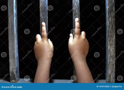 Hands Of A Young Child Clutching Prison Bars Child In Jail Stock Photo