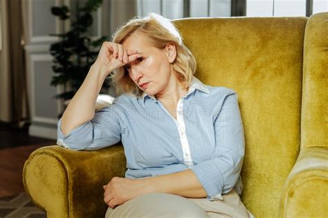 Upset Adult Woman Leaning On Her Hand While Resting In The Chair Stock