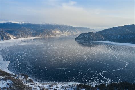 Frozen Lake Surrounded With Wooded Mountains In Snowy Winter · Free