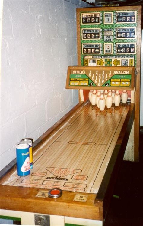 An Old Fashioned Bowling Game With Pins And Balls On The Board Next To A Can Of Beer