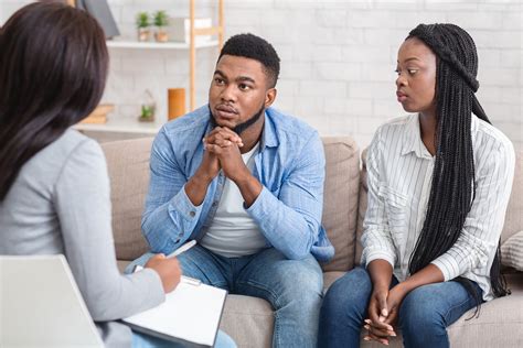 Couple Listening To Counselors Advice Sitting On Sofa During Therapy Session International