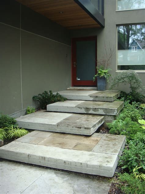 Concrete Steps Lead Up To The Front Door Of A Modern House With Plants