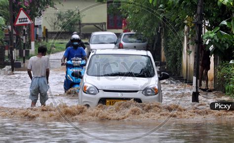 image of commuters wade through a water logged street following heavy rains in guwahati india