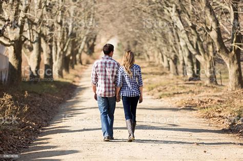 Rear View Of Couple Holding Hands Walking In Autumn Countryside Stock