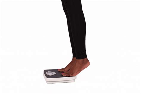 Legs Of Woman Stepping On Weigh Scale To Measure Weight