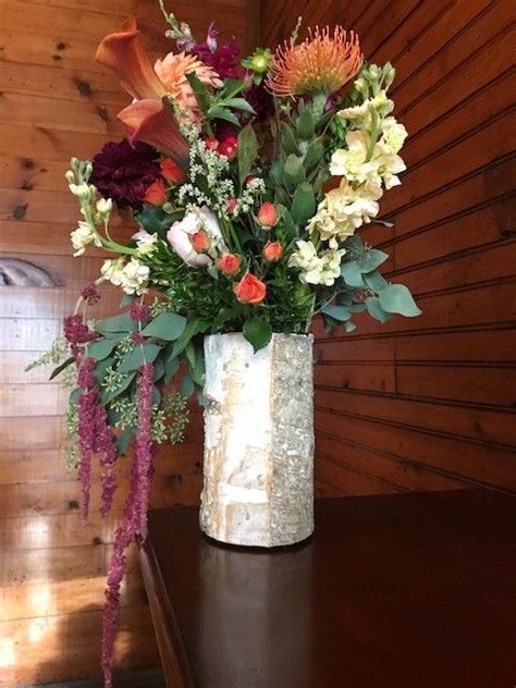 A Vase Filled With Lots Of Different Flowers On Top Of A Wooden Table