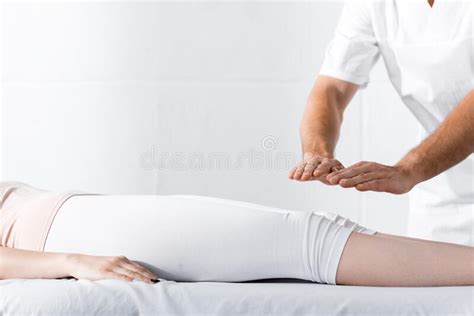 View Of Healer Standing Near Woman On Massage Table And Holding Hands