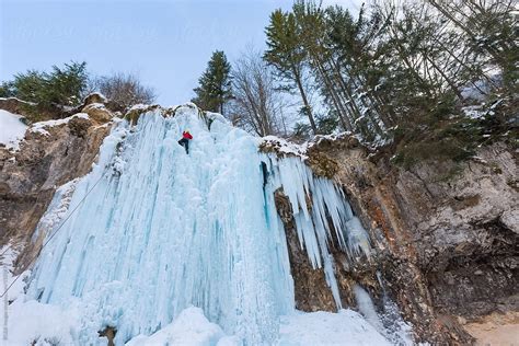 Alpinist Climbing On Frozen Waterfall In Beautiful Natural Scene By