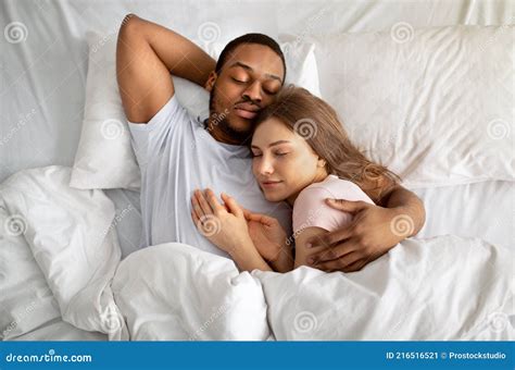 Affectionate Interracial Couple Sleeping In Bed And Hugging Top View