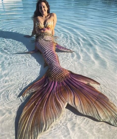 A Woman Is Laying In The Water With A Mermaid Tail