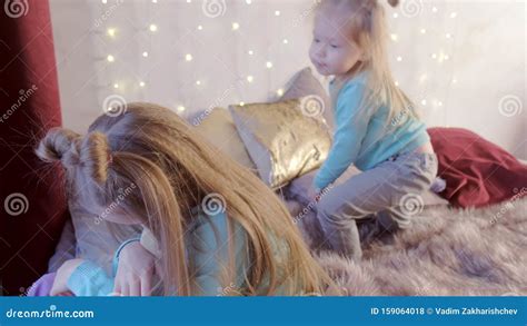 Younger Sister Cuddling Her Older Sister Teenager Sitting In Bed With