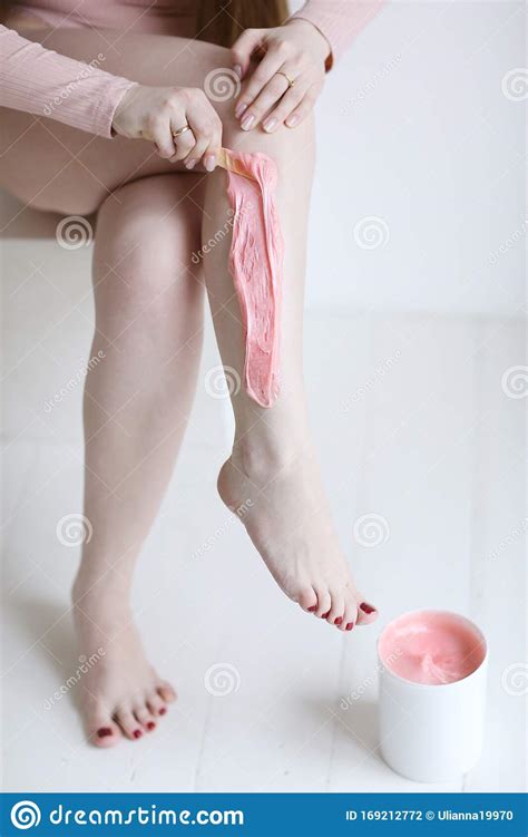 girl cosmetitian with pink sugar paste for sugaring depilation close up photo with bare legs