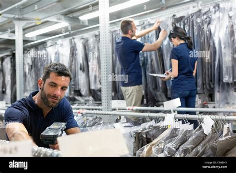 Three Warehouse Workers Preparing Garments In Distribution Warehouse