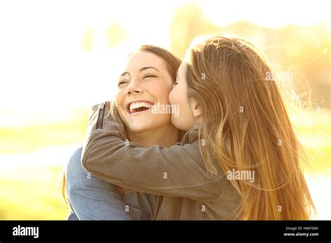 Two Happy Friends Hugging And Kissing In The Street At Sunset With A
