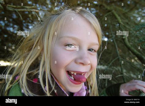 A Smiling Girl Hides In Her Tree Fort Sticking Her Tongue Out Between Her Missing Teeth Stock