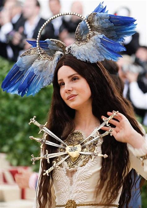A Woman With Long Brown Hair And Blue Feathers On Her Head Wearing A Costume