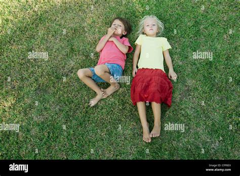 Children Lying Together On Grass Looking Up At Camera Stock Photo Alamy