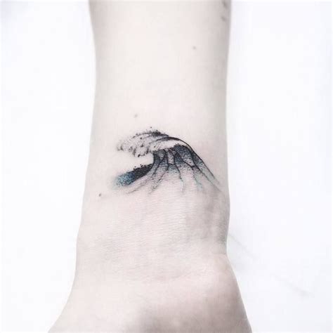 A Small Wave Tattoo On The Wrist Is Shown In Black And Grey Ink With