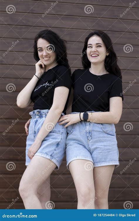 Dos Jóvenes Morenas Con Una Camiseta Negra Y Pantalones Cortos De Denim Abrazándose Hermanas