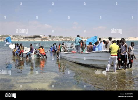 Residents Of Mogadishu Stand Around Lido Beaches Lifeboats On A