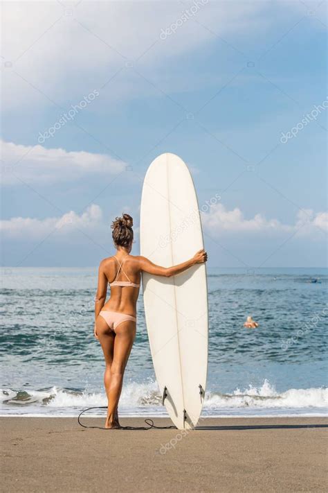 Surf chica con el pelo largo ir al océano Mujer sosteniendo tabla de surf en una playa