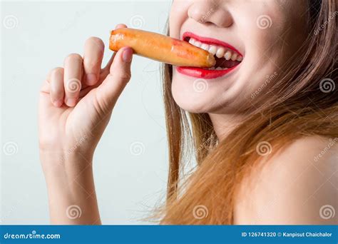 Young Woman Eating Sausage Or Hotdog Girl Is Sitting In The Kitchen