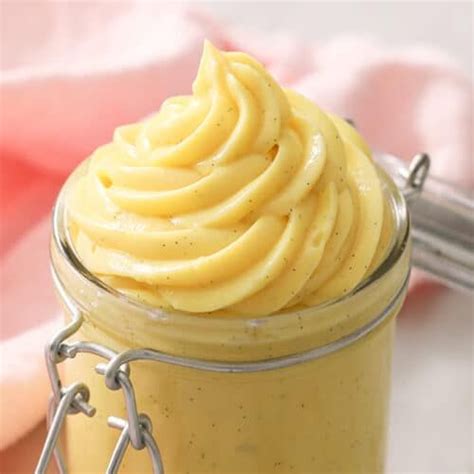 A Jar Filled With Yellow Frosting Sitting On Top Of A Table
