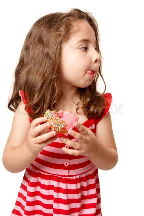Ein kleines Mädchen genießt einen süßen rosa iced donut Sie leckte sich Lippen und suchen