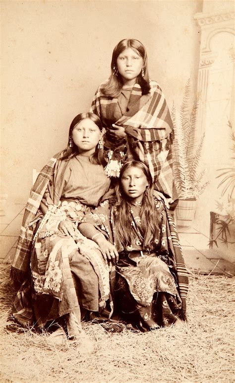An Old Black And White Photo Of Three Native American Women Sitting On