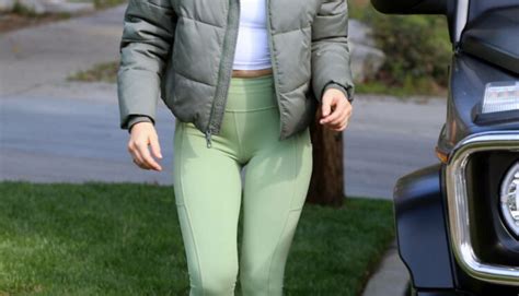 Lucy Hale Wears A Down Jacket With A White Crop Top And Green Leggings