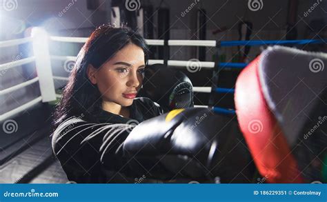 a beautiful girl in boxing gloves hits her paws in the ring woman is training in the gym