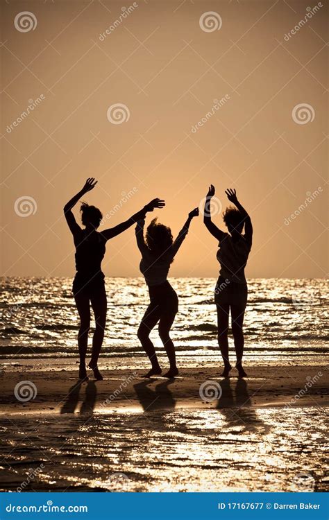 Tres Mujeres Jovenes Que Bailan En La Playa En La Puesta Del Sol Imagen