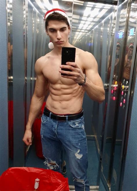 A Shirtless Man Taking A Selfie In The Mirror With His Cell Phone And Hat On