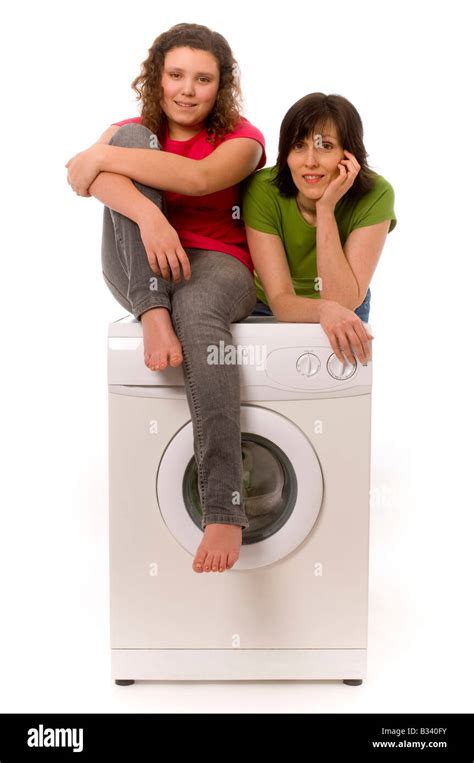 Mother And Daughter Leaning On Washing Machine Looking Happy Stock