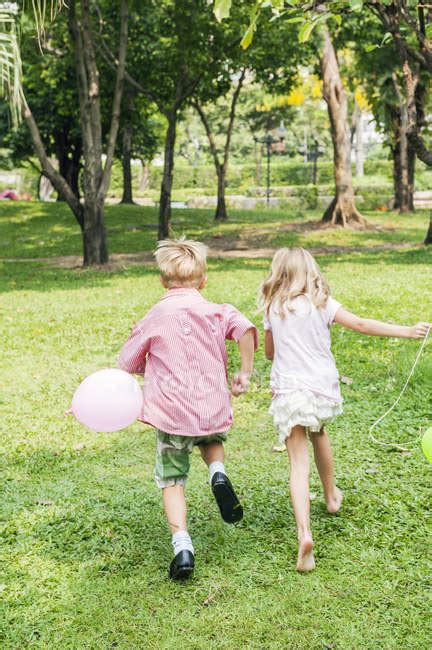 Vue Arrière Des Enfants Qui Courent Avec Des Ballons Dans Le Parc